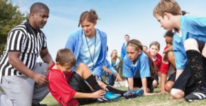 Soccer officials helping injured player during kids’ game